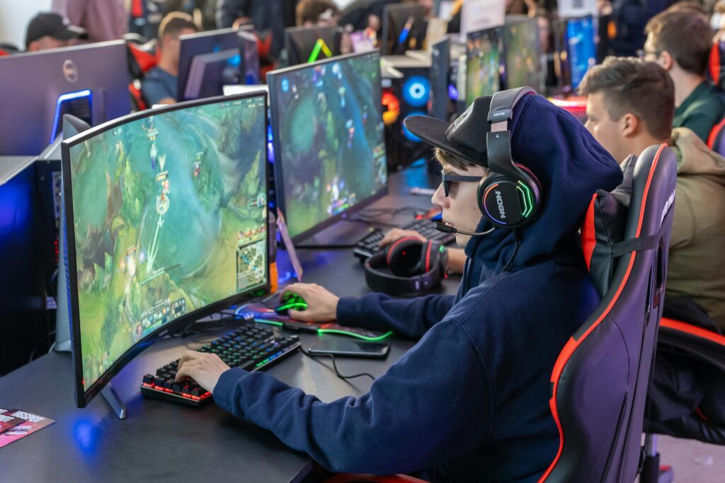 Gamers in an esports tournament playing on high-end gaming setups with monitors, keyboards, and headphones.