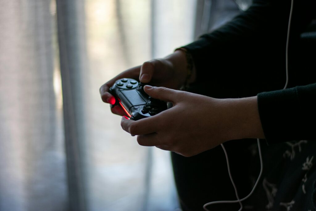 Close-up of hands holding a video game controller in a dimly lit room.