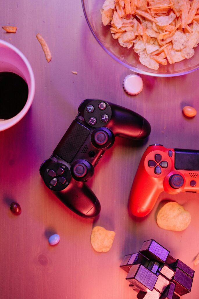 Top view of a gaming setup with controllers and snacks, enhanced by vibrant lighting.